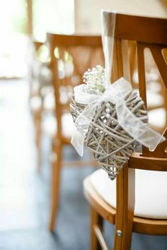 a bunch of chairs that have some flowers on top of each chair and ribbons tied to them