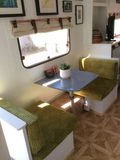 the inside of a mobile home with two green chairs and a blue table in front of it