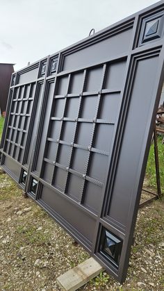 a large metal sign sitting on top of a grass covered field next to a building