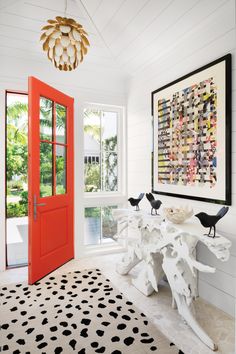 a white room with black and white rugs, red door and two birds on the table