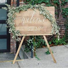 a wooden welcome sign with greenery on it