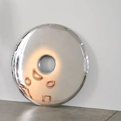 a large metal object on the ground near a white wall with an orange light in it