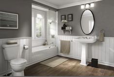 a bathroom with gray walls and white fixtures, including a sink, toilet, tub, and mirror