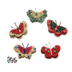 four red and green butterfly brooches sitting on top of each other