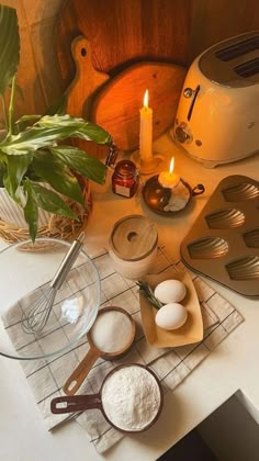 an assortment of ingredients on a table with a lit candle in the middle and other kitchen utensils next to it