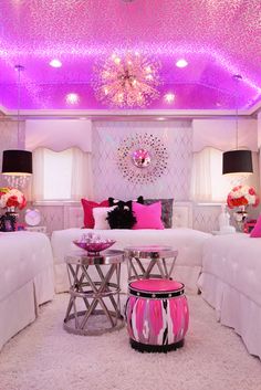 a living room filled with lots of white furniture and pink lighting above the couches