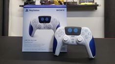 two video game controllers sitting on top of a table next to a box that says sony