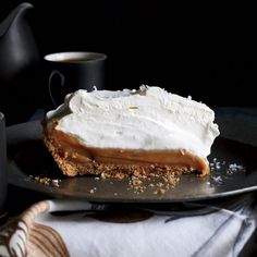 a piece of pie with whipped cream on top and coffee in the backgroung