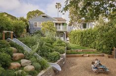 two people sitting on a bench in the middle of a garden with rocks and plants