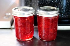 two jars filled with red liquid sitting on top of a counter