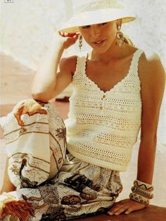 a woman sitting on the ground wearing a white hat and holding a purse in her hand