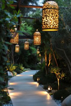 an outdoor walkway with lanterns hanging from it's sides and trees in the background