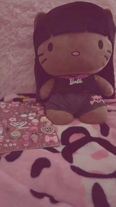 a hello kitty stuffed animal sitting on top of a bed next to a pink blanket