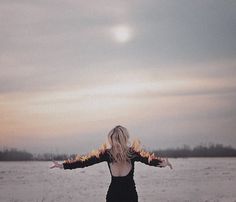 a woman standing in front of a body of water with her arms spread wide open