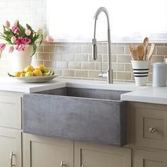 a bowl of lemons and tulips on a counter in a white kitchen