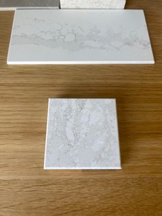 three different types of marble tiles on top of a wooden table, one white and the other gray