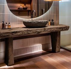 a wooden table with a bowl on it in front of a mirror and light fixture