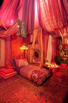 a bedroom decorated in pink and red with lights on the ceiling, bed covered in fabric