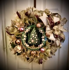 a christmas wreath hanging on the front door with ornaments around it and ribbons attached to it