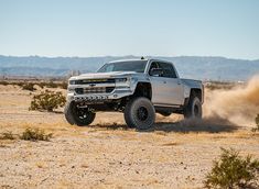 a silver truck is driving through the desert