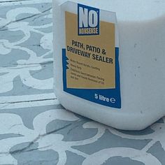 a bottle of patch and driveway sealer sitting on a tile floor in front of a wall