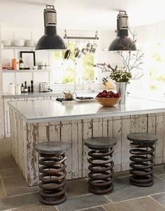 a kitchen island with three stools in front of it and two lights hanging from the ceiling