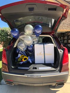 the trunk of a car with balloons and gifts in it