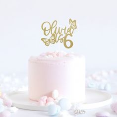 a pink cake topped with a gold glitter butterfly topper and the number six on it