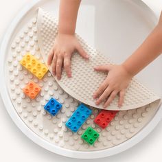 a child's hands on a lego tray