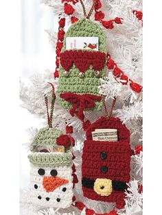 three crocheted christmas ornaments hanging from a white tree with red and green trim