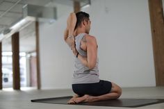 a man sitting on top of a yoga mat holding his arm up in the air