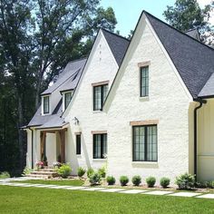 a white brick house with black roof and windows