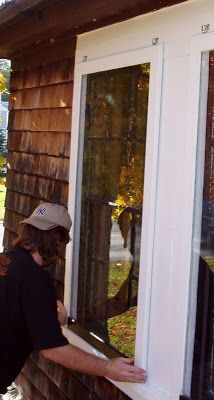 a man that is standing in front of a window with a hat on his head