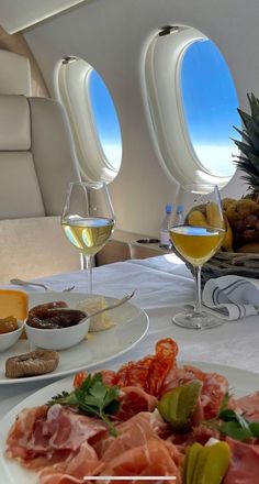 the table is set with food and wine for two people to enjoy on an airplane