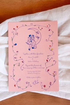 a pink wedding card with an image of two people sitting on the moon and holding hands