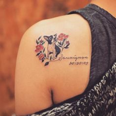 the back of a woman's shoulder with a dog and flowers tattoo on it