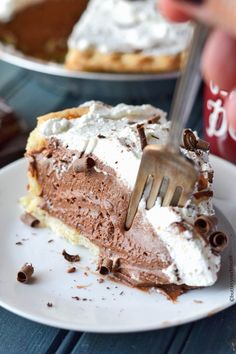 a piece of chocolate pie with whipped cream on top is being cut by a fork