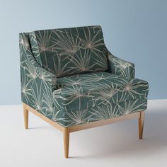 a green chair with white flowers on it and a blue wall in the back ground