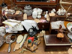 an assortment of antique items on display in front of a mirror and wooden table top