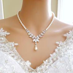 a woman wearing a necklace with pearls and a pearl drop on it's neck