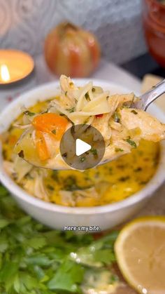 a spoon full of soup sitting on top of a table next to sliced lemons