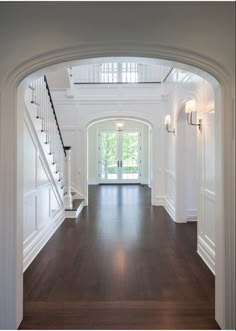 an archway leading to the second floor in a house with hardwood floors and white walls