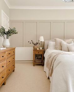 a bedroom with a bed, dresser and lamp on the side table in front of it