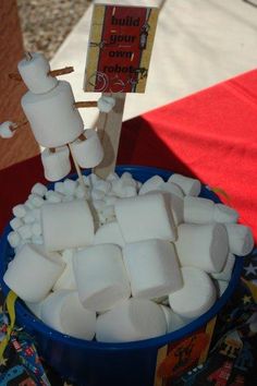 marshmallows in a blue bowl on a table with a sign and red cloth