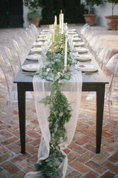 a long table with candles and greenery on it