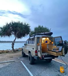 an suv is parked in a parking lot next to the ocean with its doors open