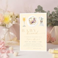 a baby shower is set up on a table next to flowers and champagne glasses,