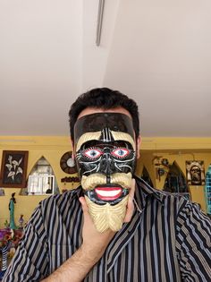 a man holding up a mask with his face painted black and white in front of him