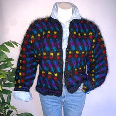 a woman's sweater with multicolored squares on it and a white shirt underneath