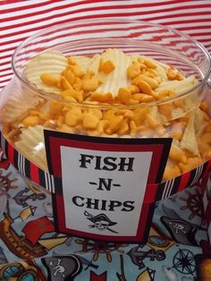 fish n chips in a glass bowl on top of a table with red and white striped cloth